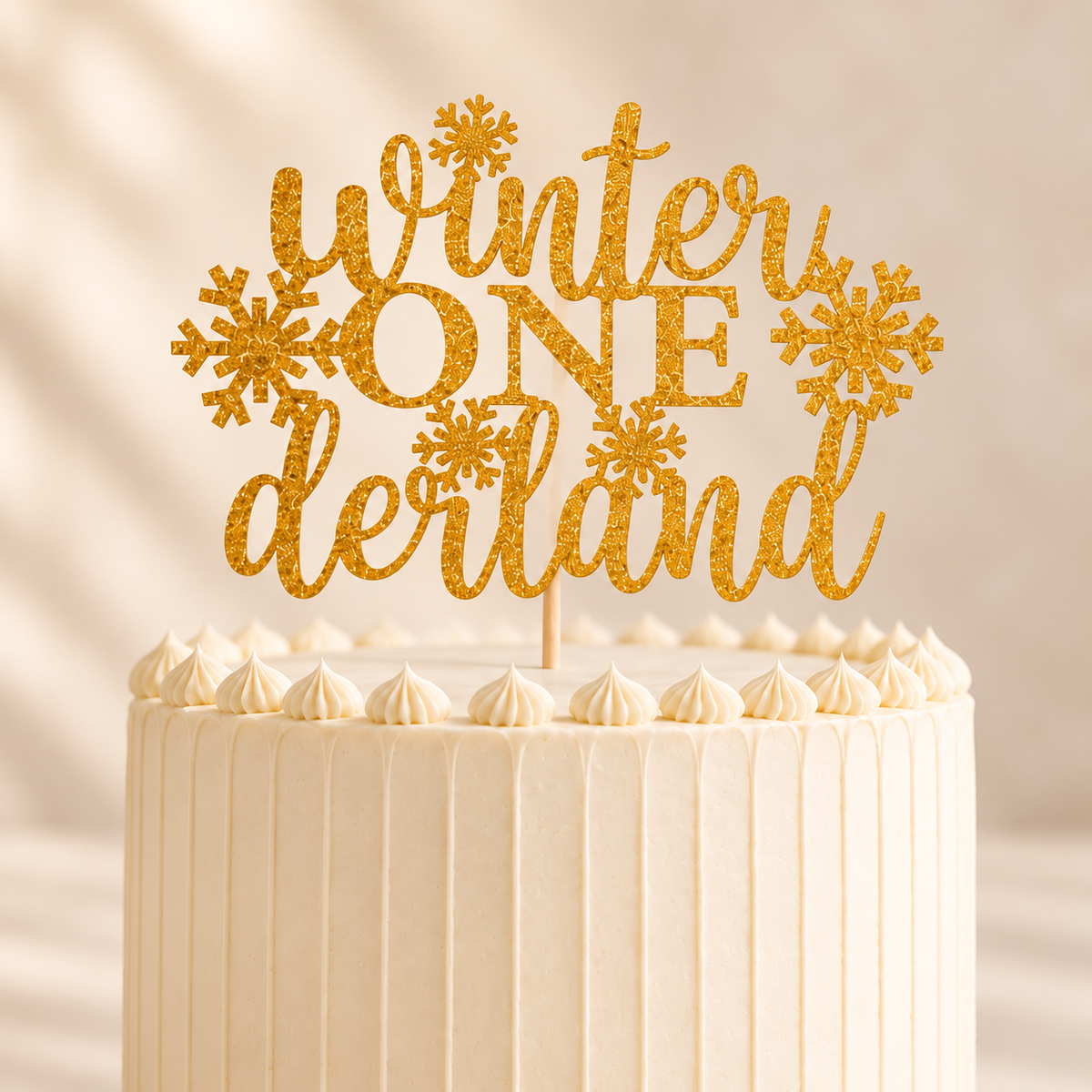 Close-up of a gold glitter Winter ONEderland cake topper on an ivory buttercream cake