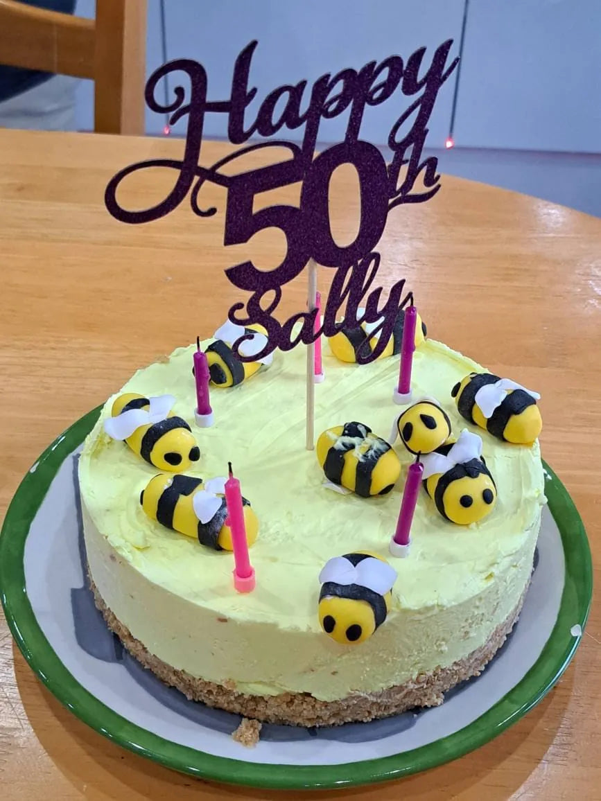 Purple personalised Happy 50th Sally cake topper on a birthday cake