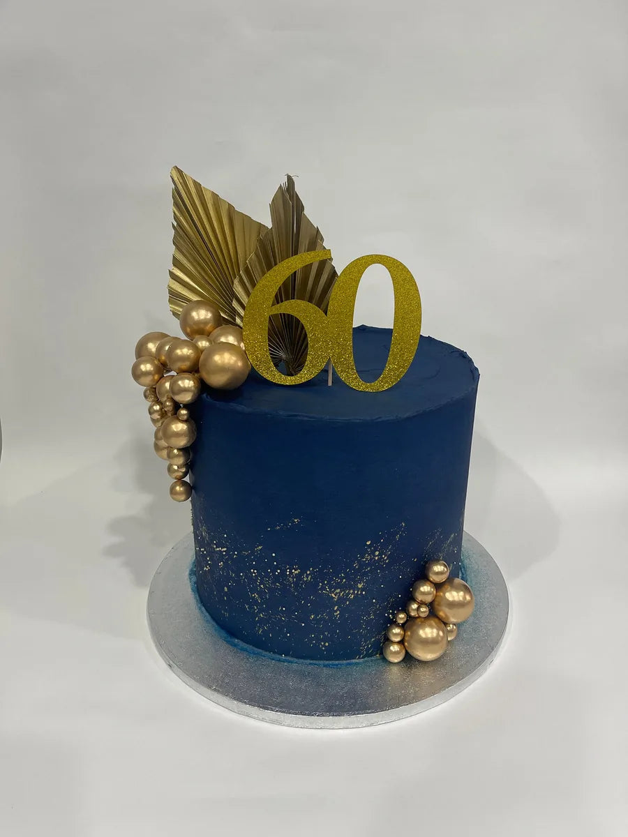 Gold glitter number 60 topper on a navy blue cake with gold decorations